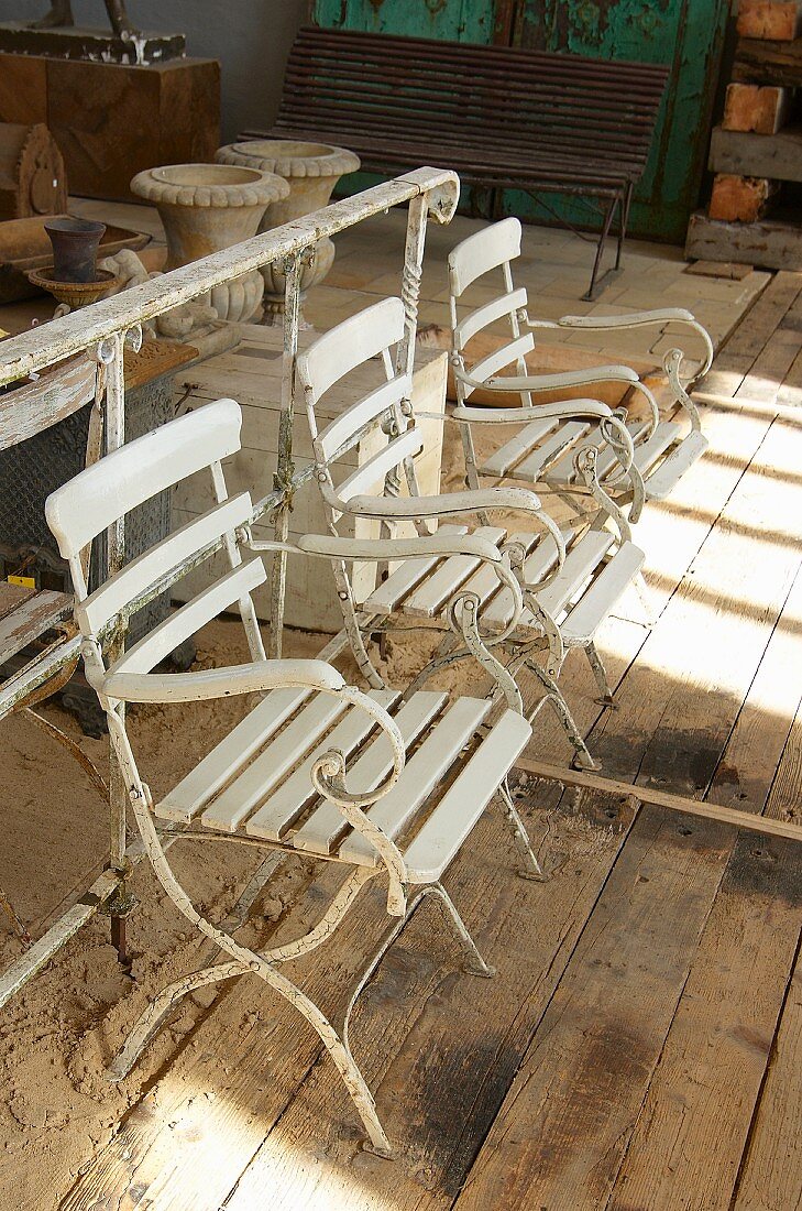 weiße Vintage Gartenstühle auf rustikalem Bretterboden