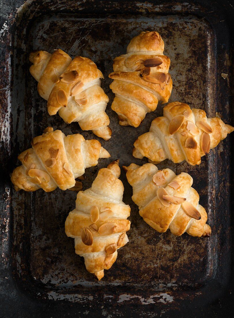 Croissants with almond flakes on a baking sheet