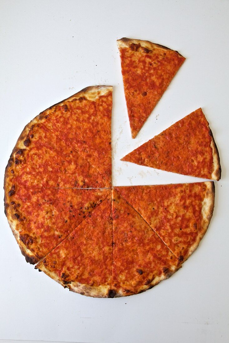 A sliced thin-crust pizza on a white background (seen from above)