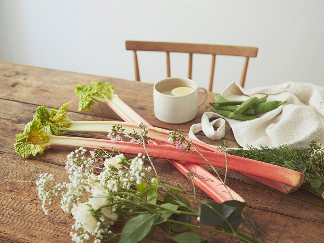 Rhabarberstangen und Blumen auf Holztisch