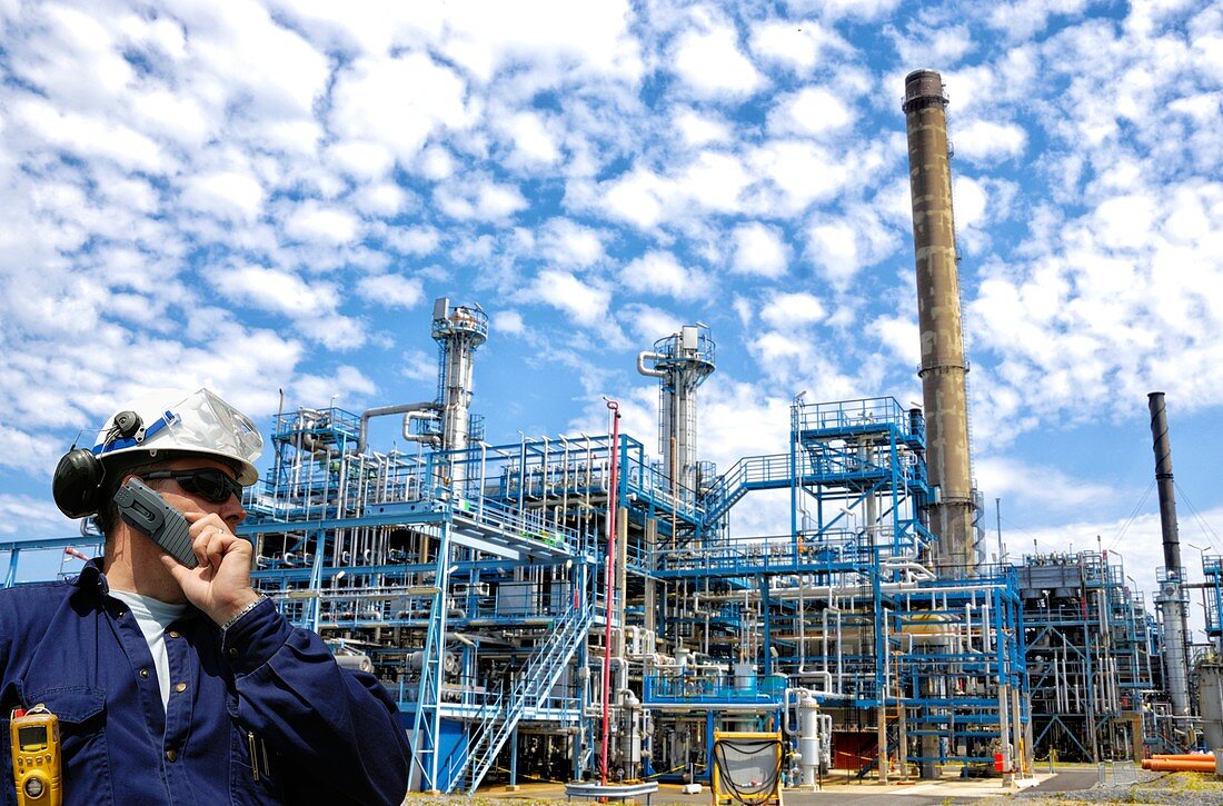 Industrial worker on oil and gas refinery using cell phone