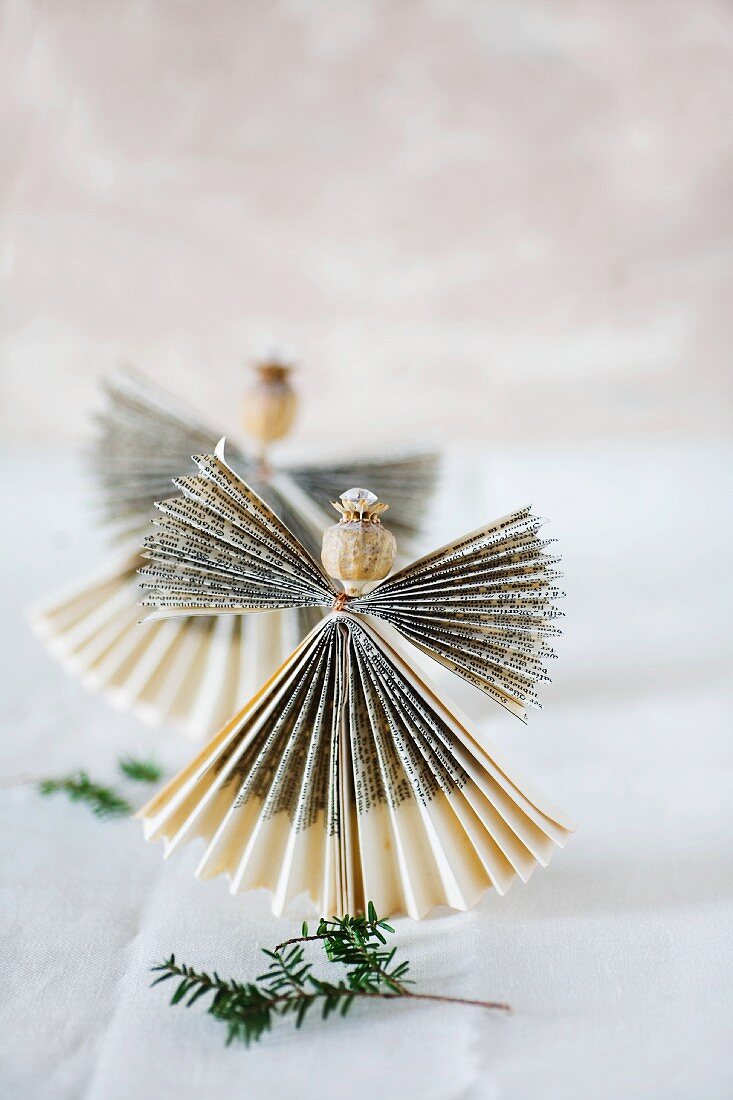 Angel made from folded paper with head made from poppy seed capsule