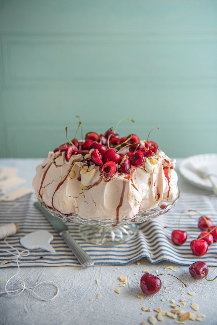 Pavlova with cream, almonds, cherries and cherry sauce