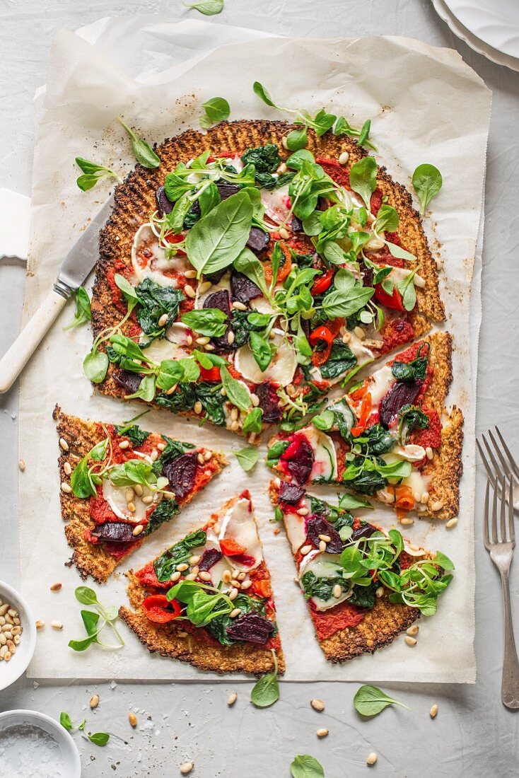 Cauliflower pizza with goat's cheese, roasted beetroot, spinach and pine nuts