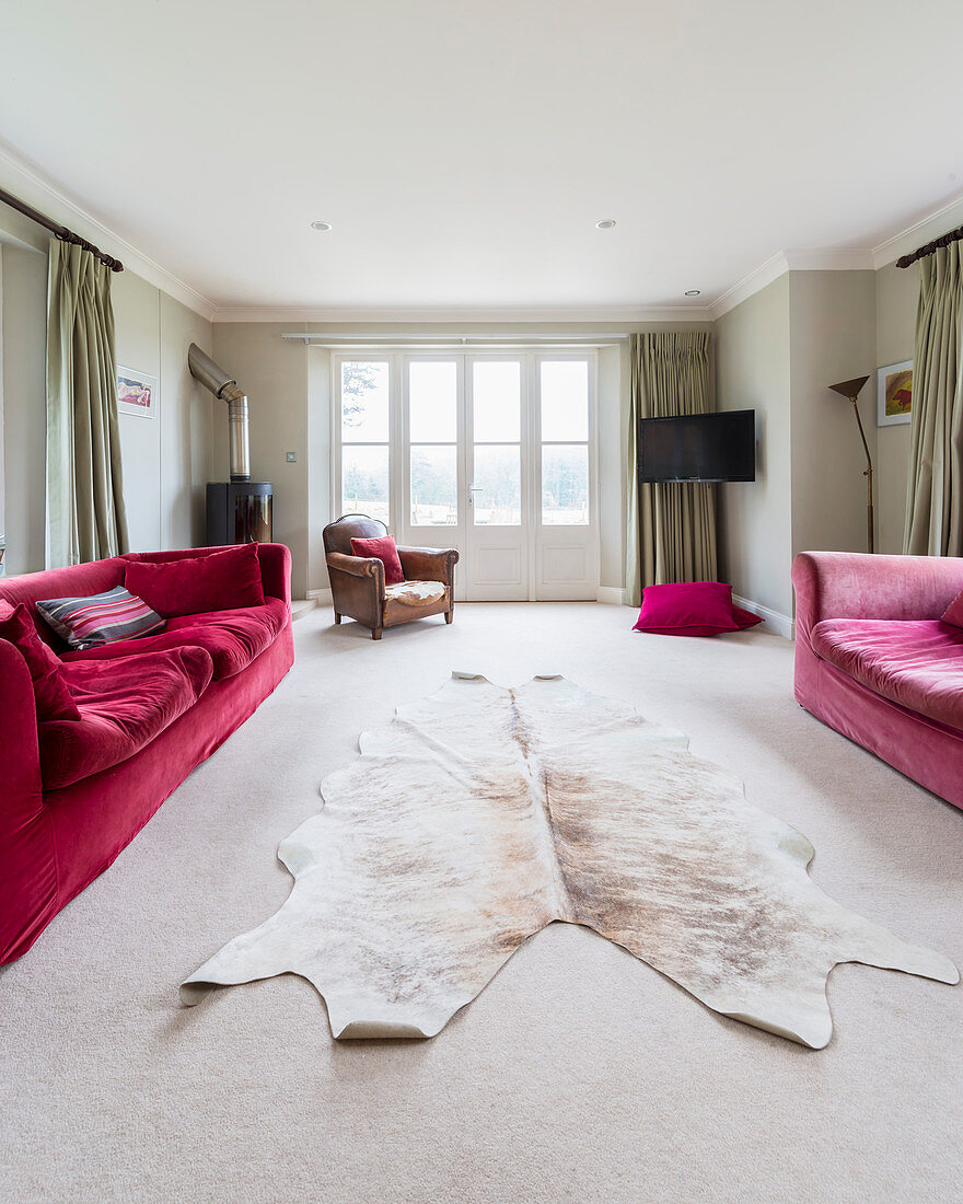 Cowhide rug between two red sofas in living room