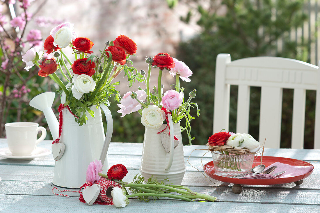 Ranunculus bouquets in watering cans and glass bowl