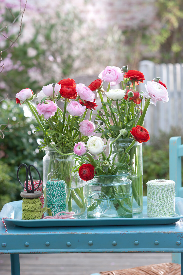 Ranunculus bouquets in preserving jars on tray