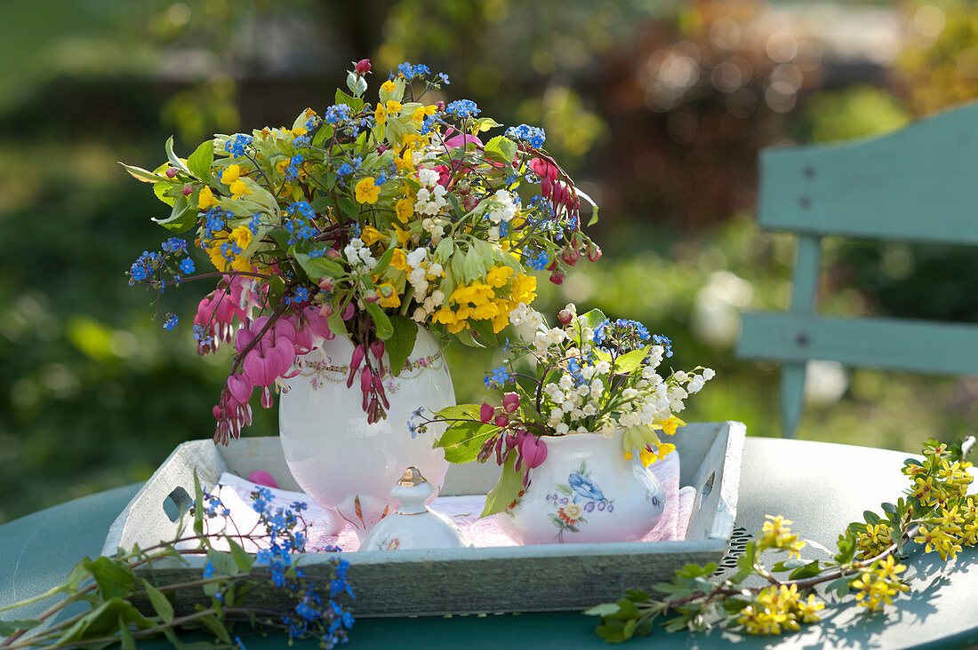 Colorful spring bouquets in jug on wooden tray