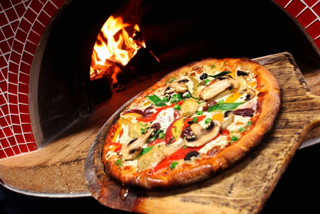 A pizza with mushrooms and courgettes cooked in a wood oven
