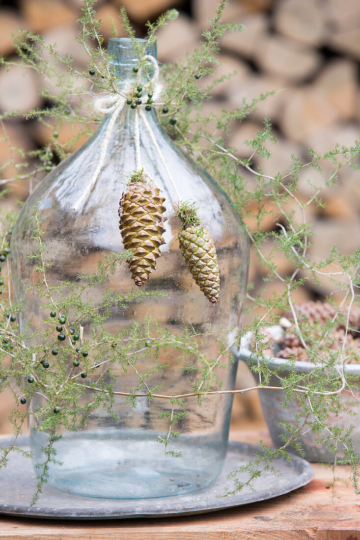 Sprigs of juniper and cones arranged around a demijohn