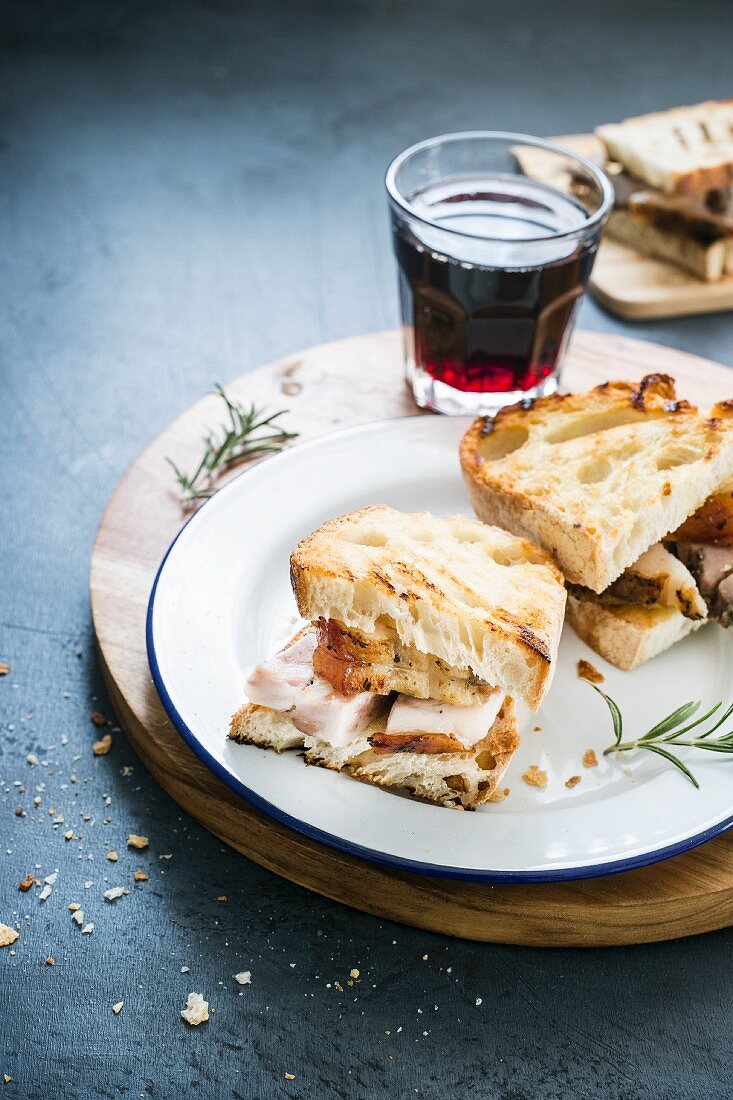 A panini with porchetta and a glass of red wine