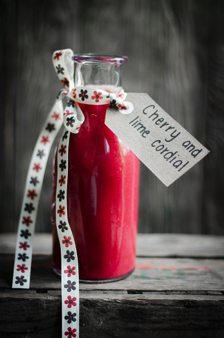 Cherry and lime cordial in a glass bottle with ribbon and a label