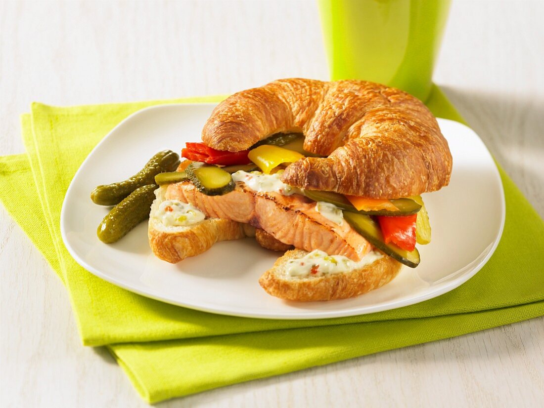 Salmon burger pickles hot peppers on a croissant