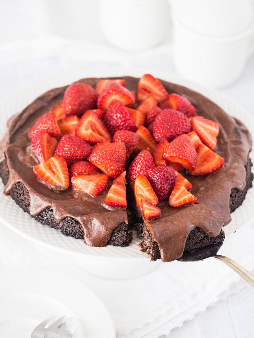 Vegan flourless (gluten free) chocolate tart with poppy seeds and chocolate frosting, served with strawberries