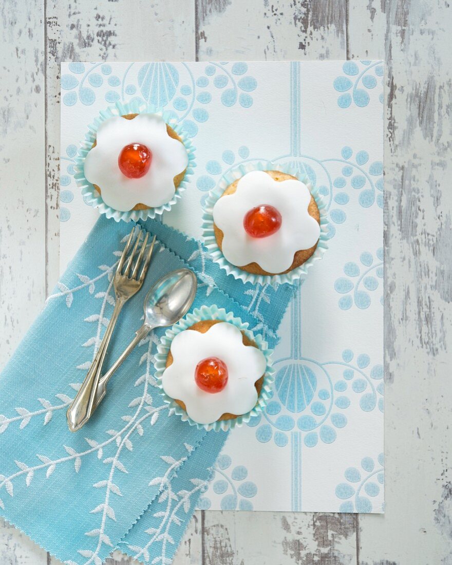Cupcakes decorated with icing and glace cherries (top view)
