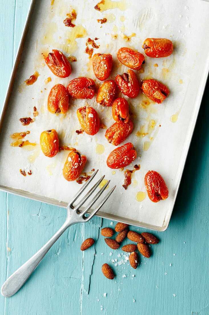 Date tomatoes sprinkled with salt and filled with almonds, on a baking sheet