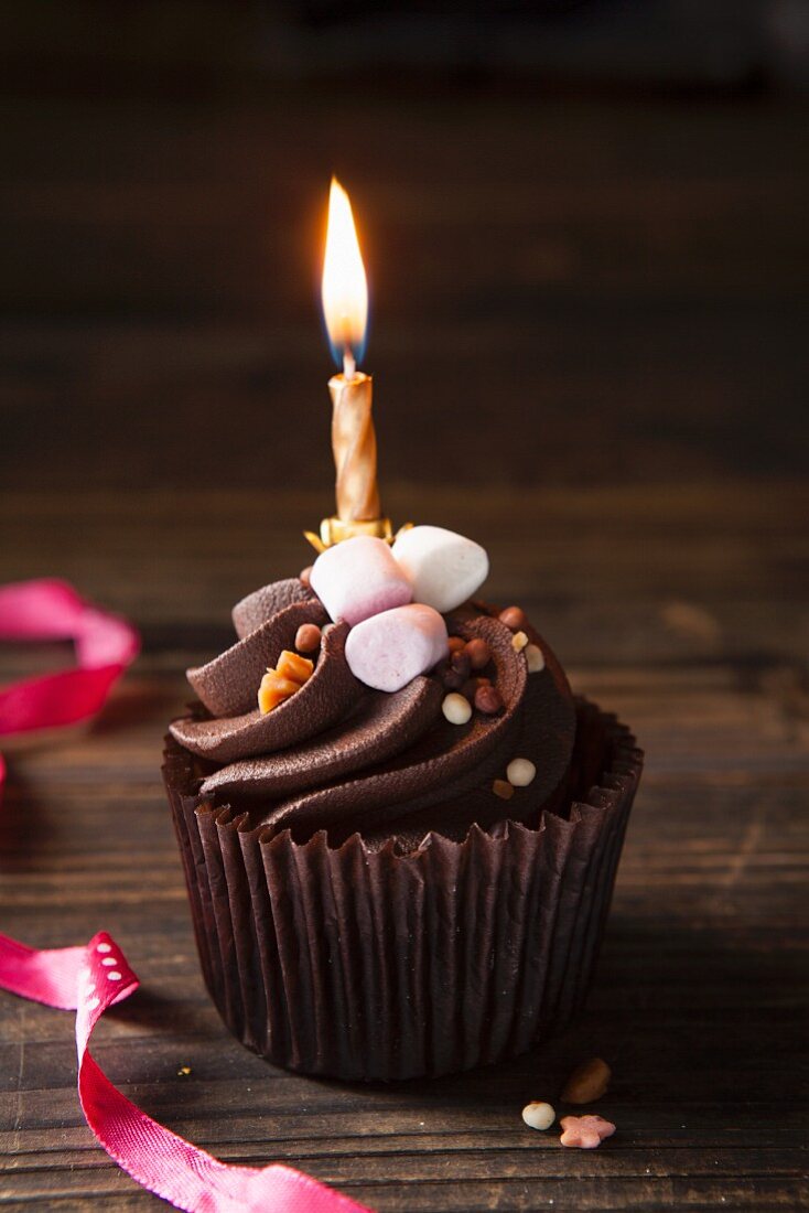 Schokoladencupcake mit Mini-Marshmallows, Toffee und Geburtstagskerze