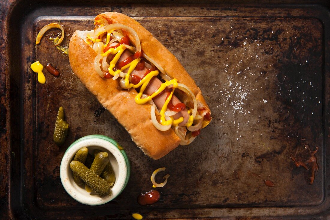 A hot dog with ketchup, mustard and fried onions served on a vintage baking tray