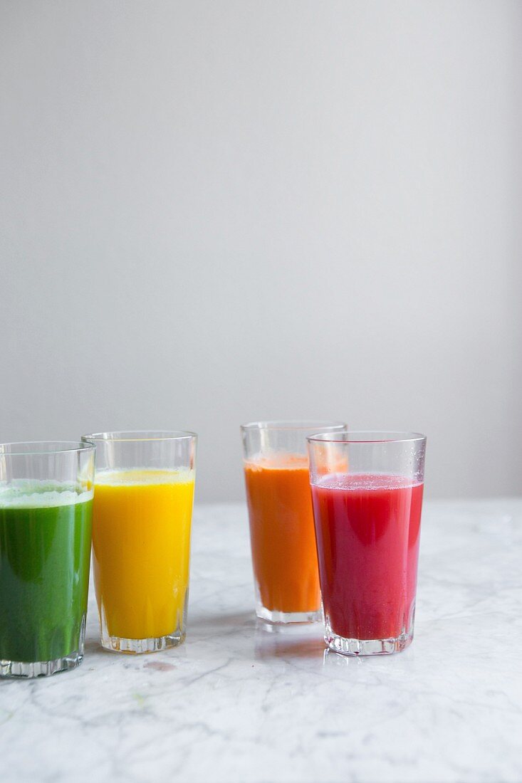 Verschiedene frische kaltgepresste Säfte (grüner Saft, Apfel-Zitronen-Saft, Karotte, Wassermelone)