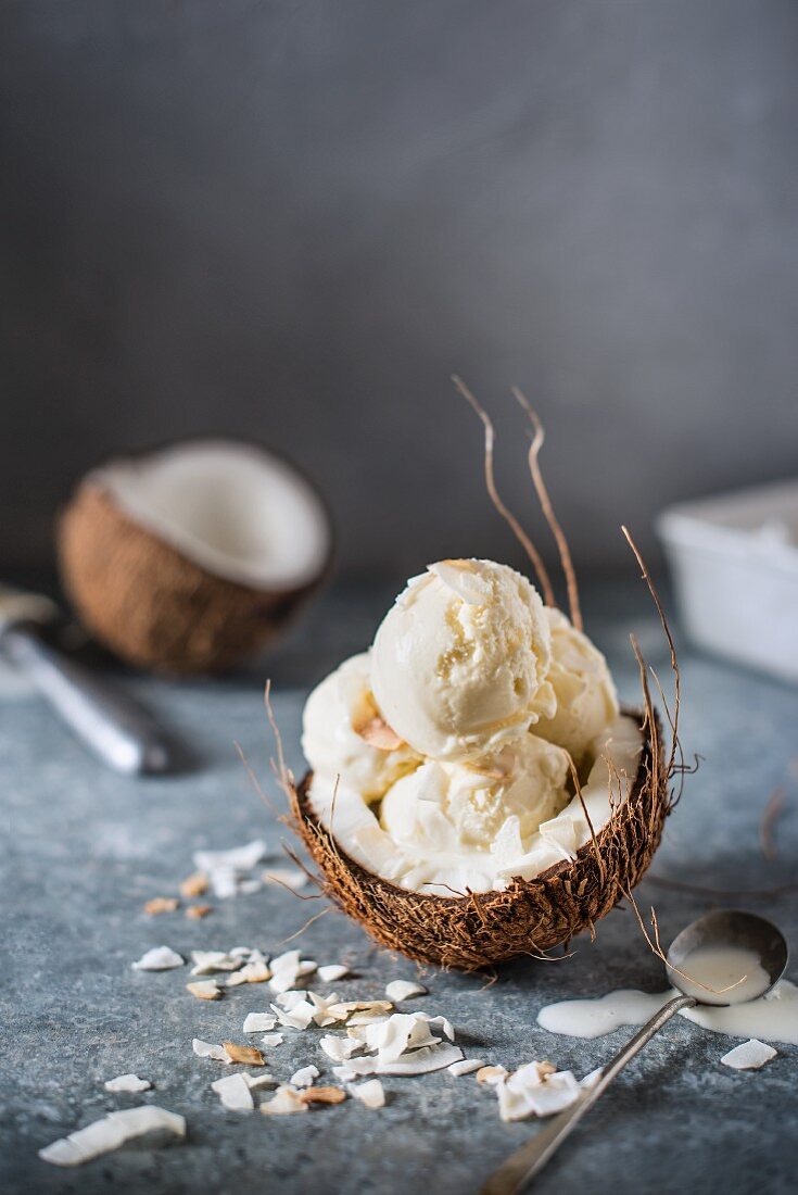 Coconut ice cream scoops in a halved coconut with coconut chips