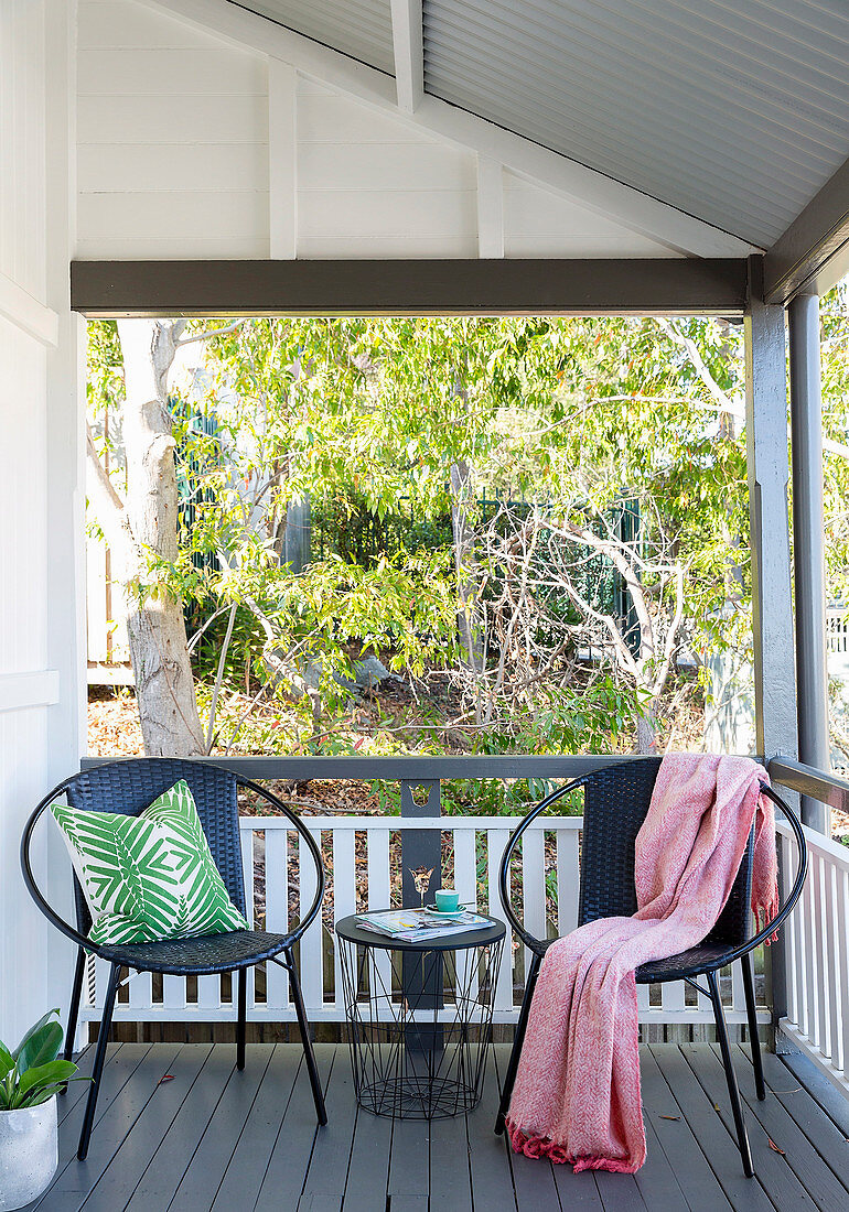 Two round chairs and a filigree table on the veranda