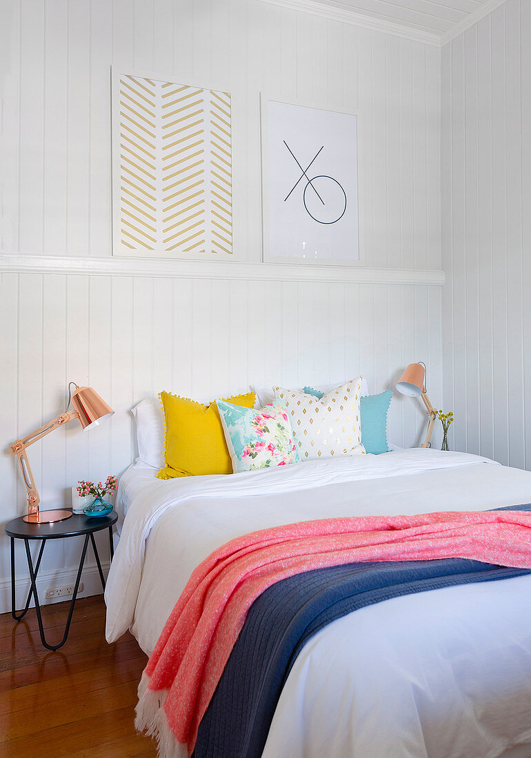 Pictures on a decorative strip above the bed with colorful pillows and plaids