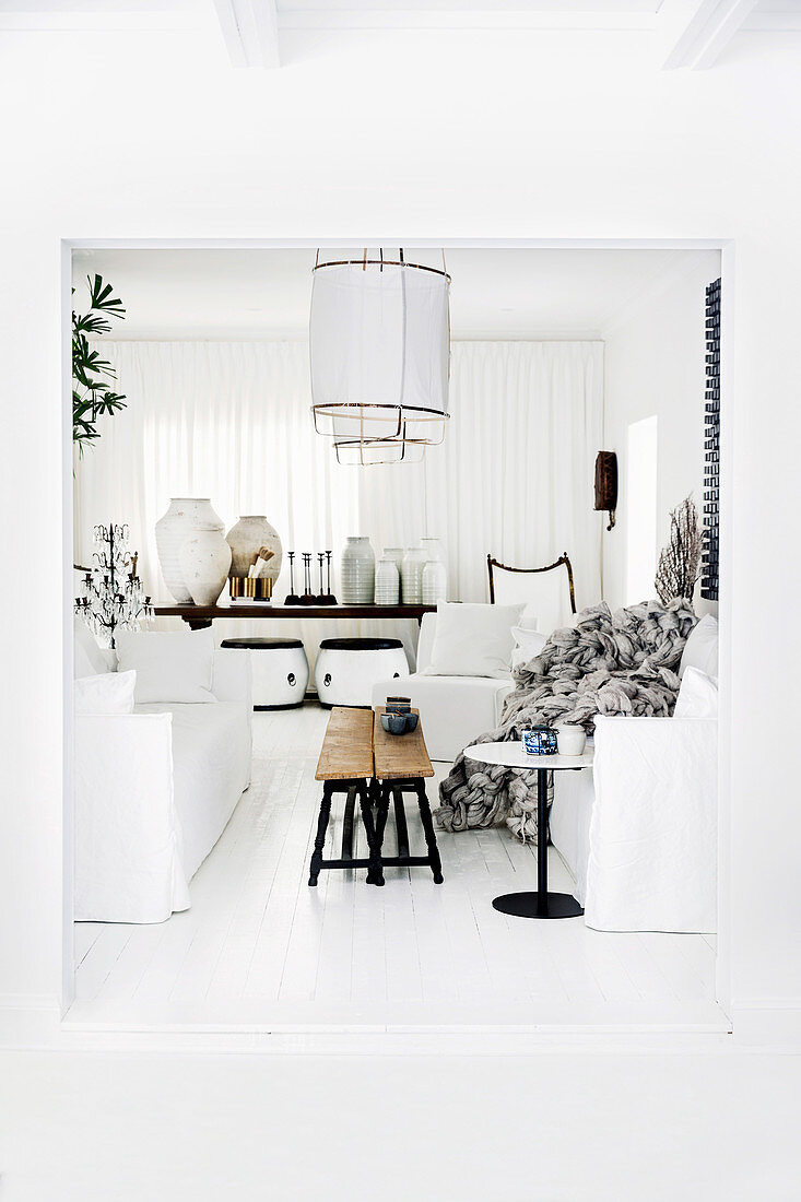 Sofa with white cover and vintage benches as a coffee table on a white floorboard