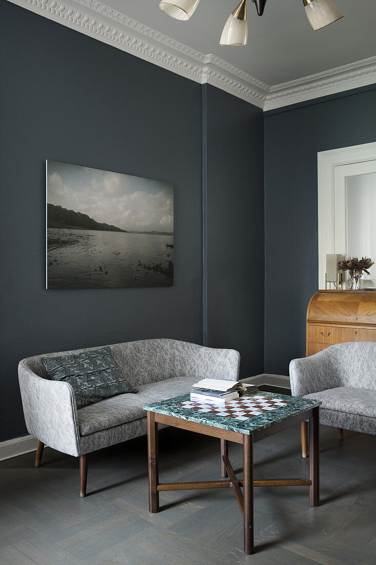 Sofa and armchair around chess table in room with grey walls