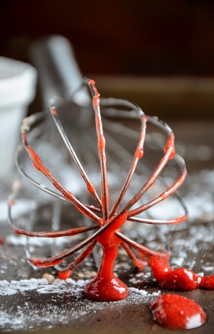 A whisk covered in Strawberry sauce
