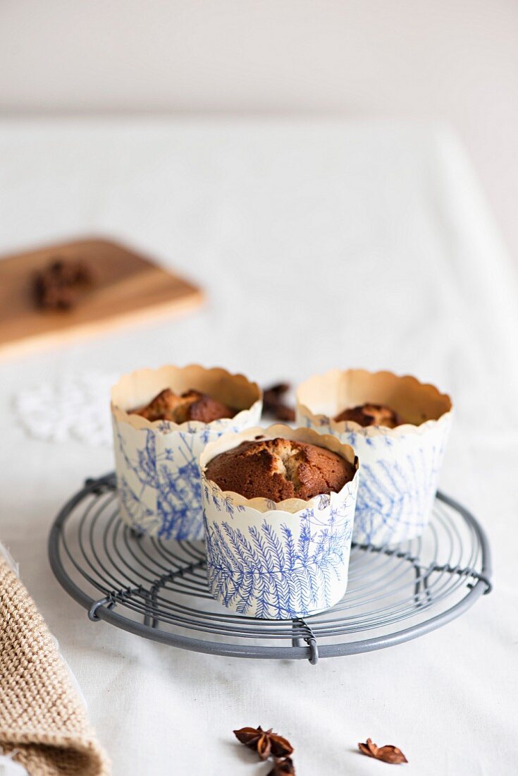 Biskuit-Muffins in Pappförmchen auf Kuchengitter