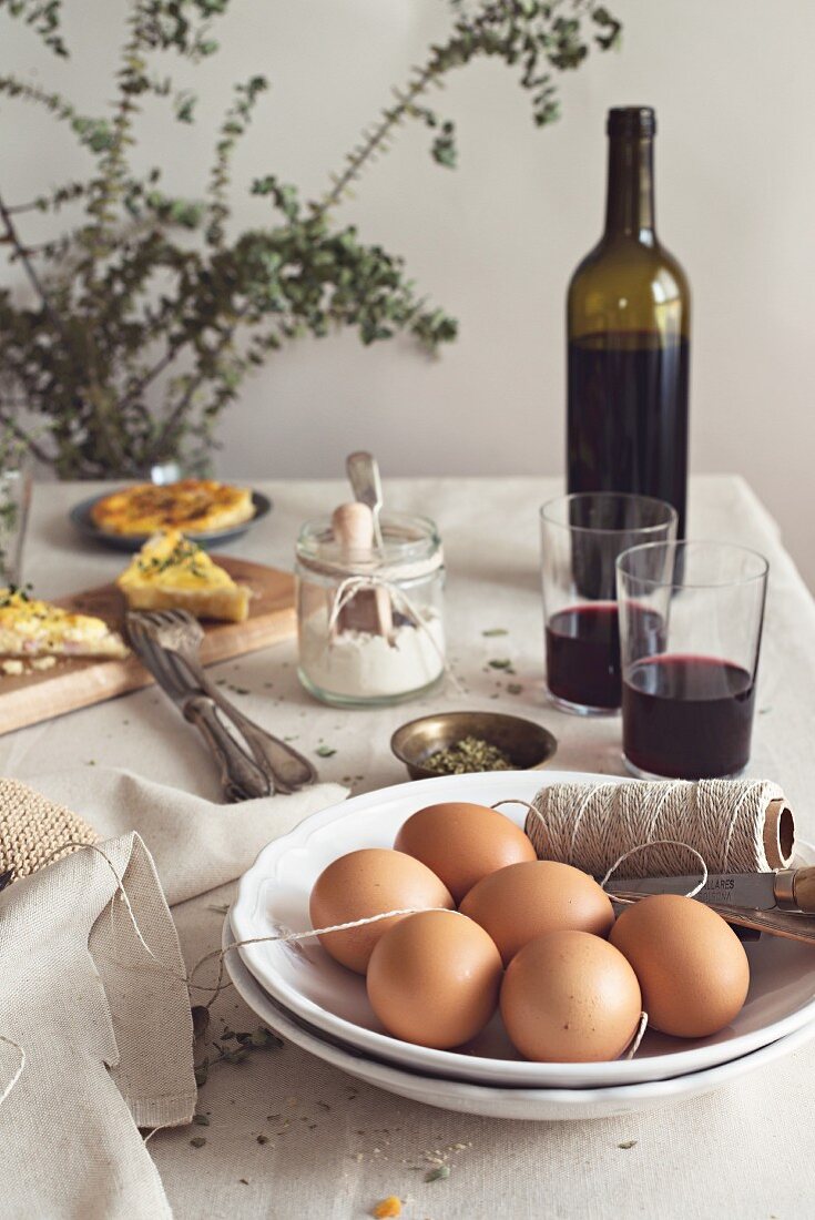 Quiche Lorraine mit Zutaten und Rotwein auf rustikalem Tisch