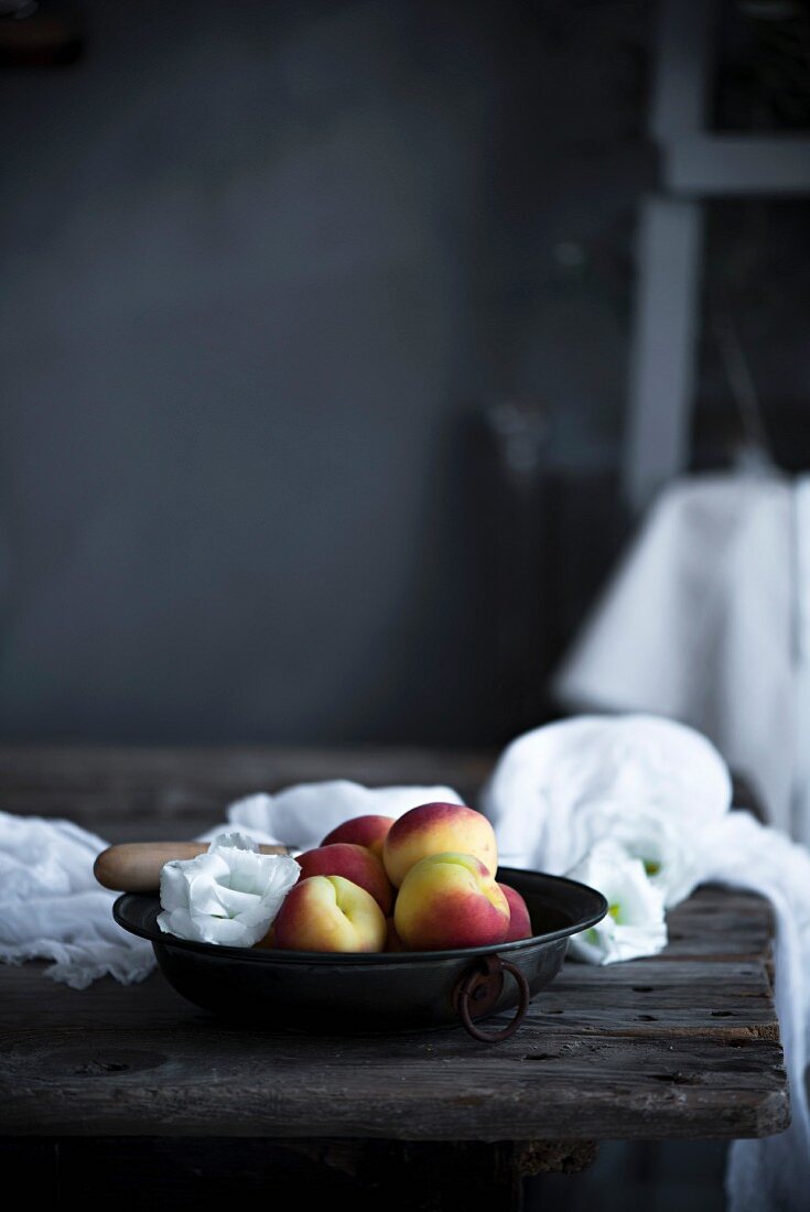 Frische Pfirsiche in Schüssel auf rustikalem Küchentisch