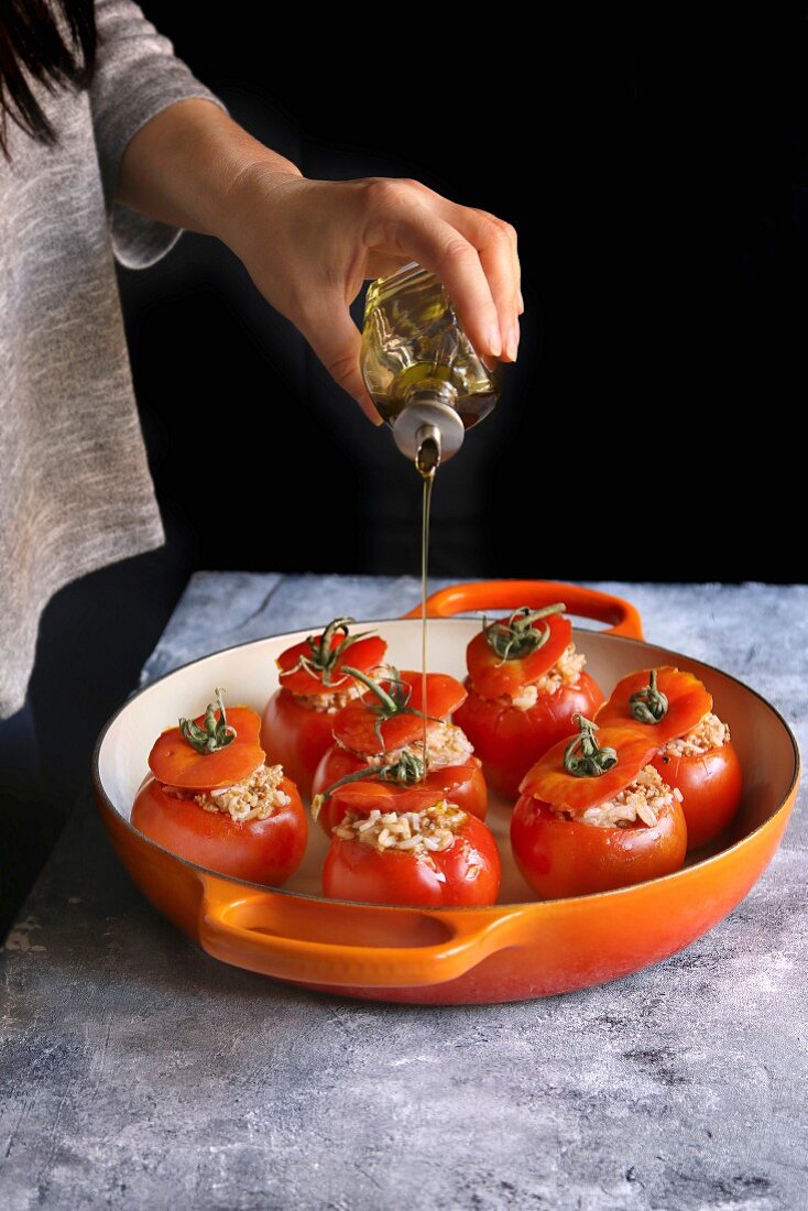 Tomaten mit Hackfleisch-Reisfüllung werden mit Olivenöl beträufelt
