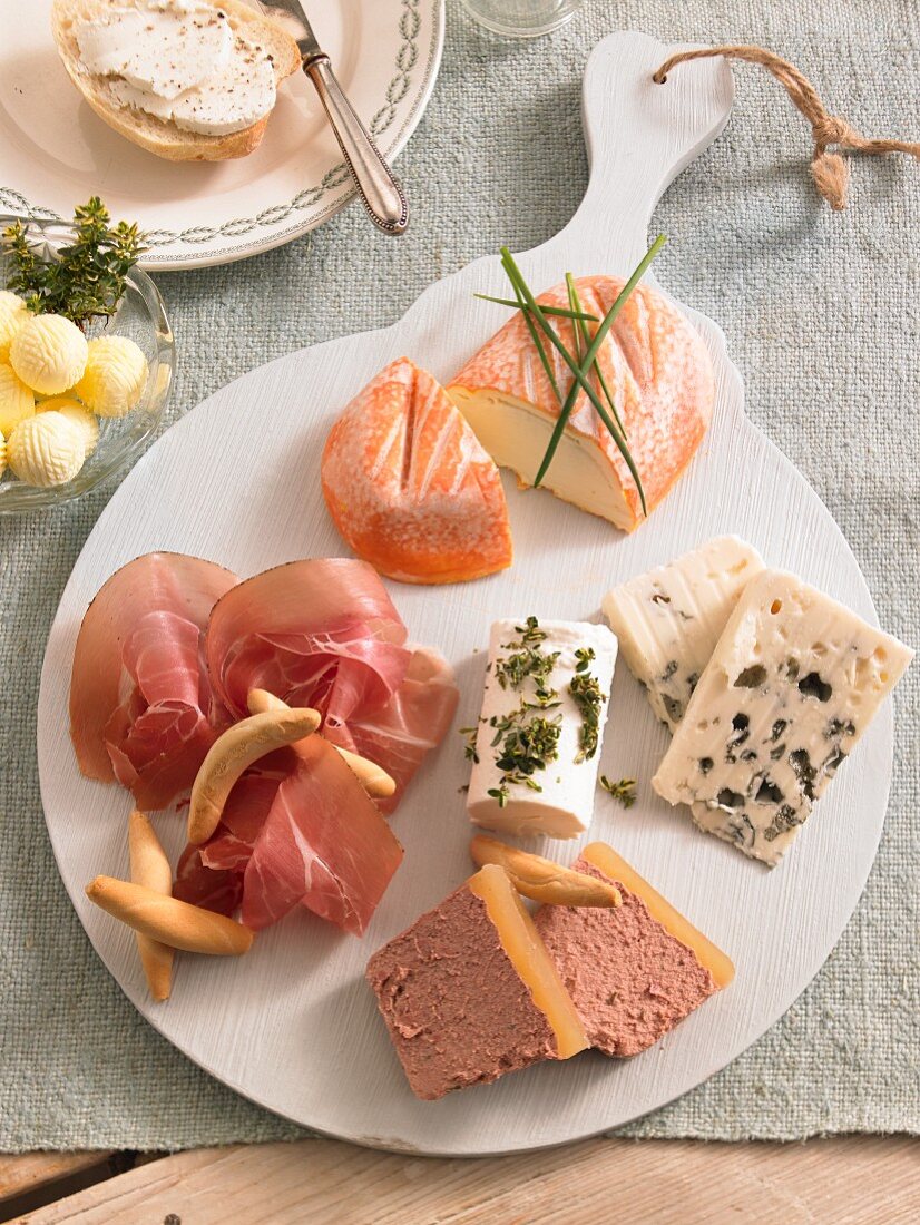A cheese plate with raw ham and butter balls for brunch