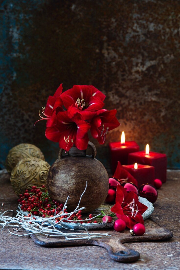 Red amaryllis in spherical vase and festive decorations on board