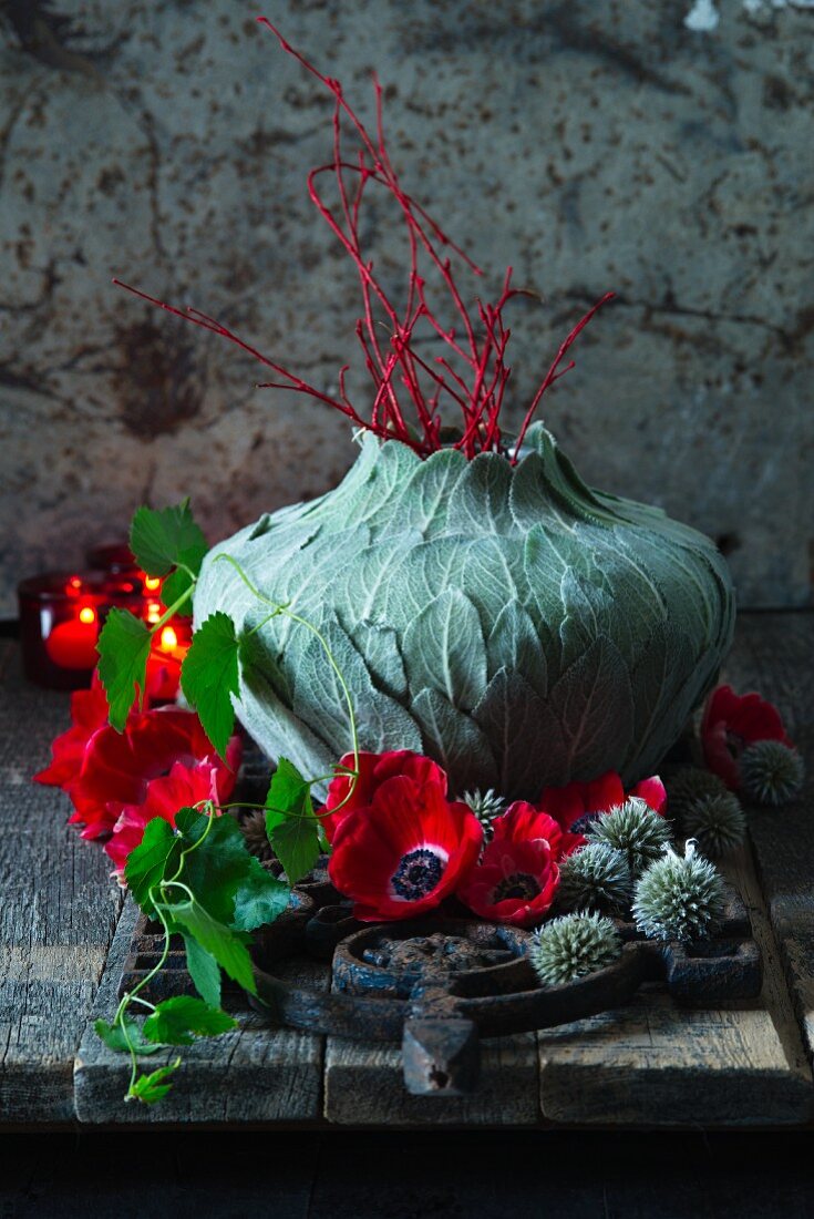 Red and grey arrangement around vase wrapped with leaves