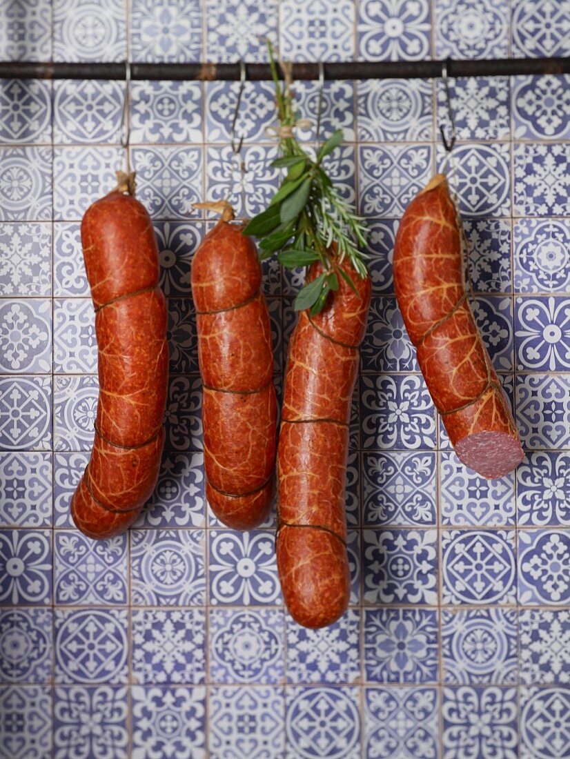 Susländer pork sausages hanging on hooks in front of a tiled wall