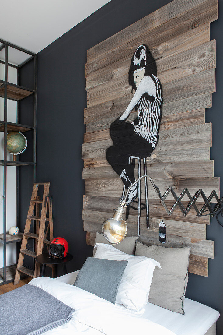 Industrial-style bedroom with artwork painted on wooden boards above bed