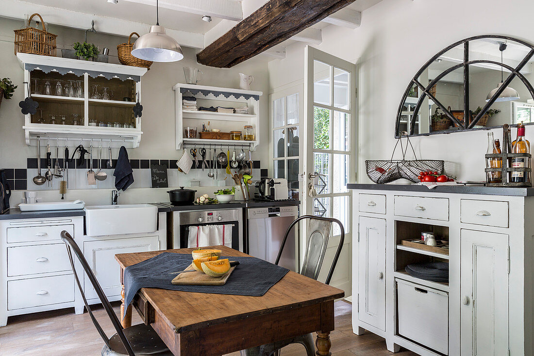 White cupboards, table and two chairs in rustic kitchen