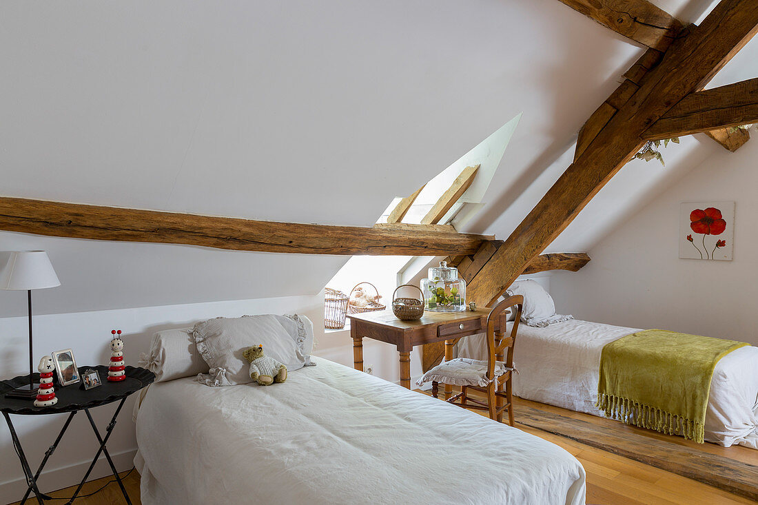 Twin beds in attic bedroom with rustic wooden beams
