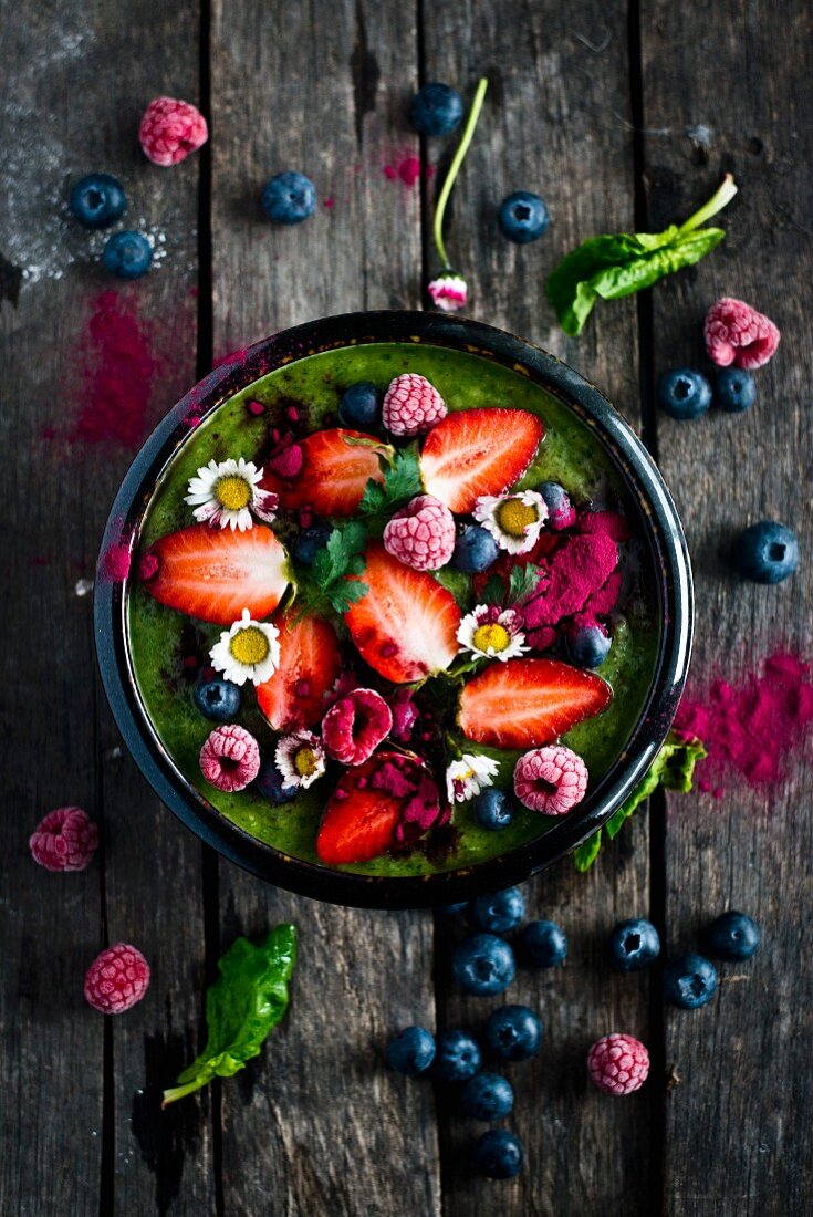 Grüne Smoothie Bowl mit Früchten und Gänseblümchen