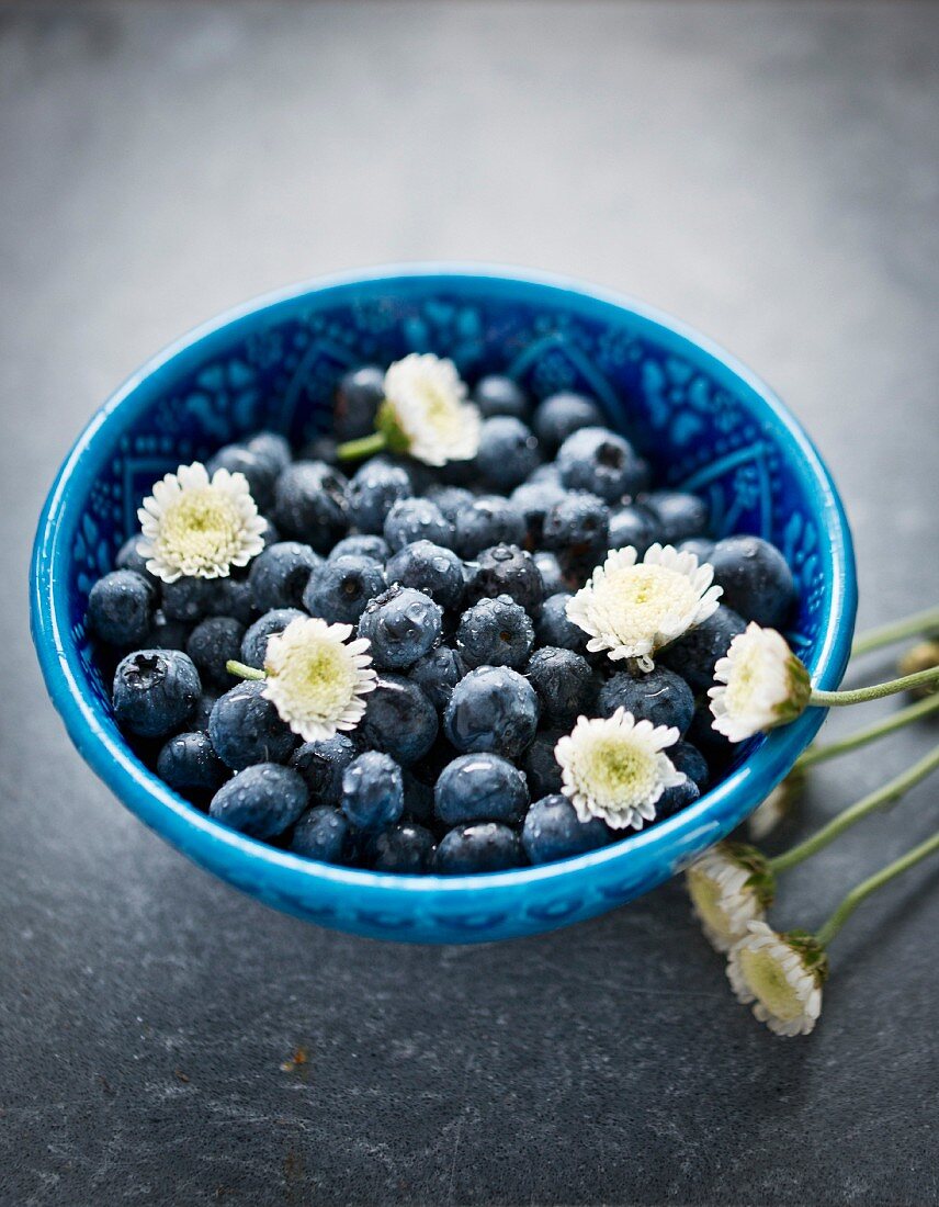 Blueberries with flowers in a blue bowl