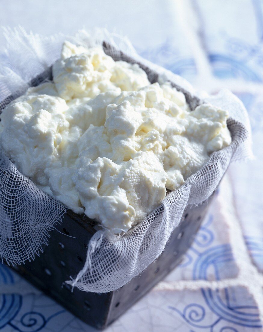 Fresh cheese on gauze cloth in a container
