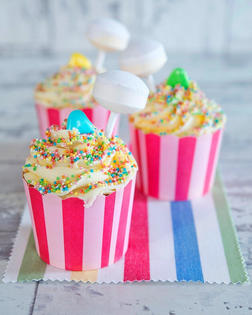 Cupcakes mit bunten Zuckerperlen und Lolli