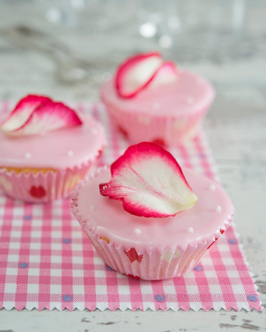 Cupcakes with pink fondant icing and a rose petal