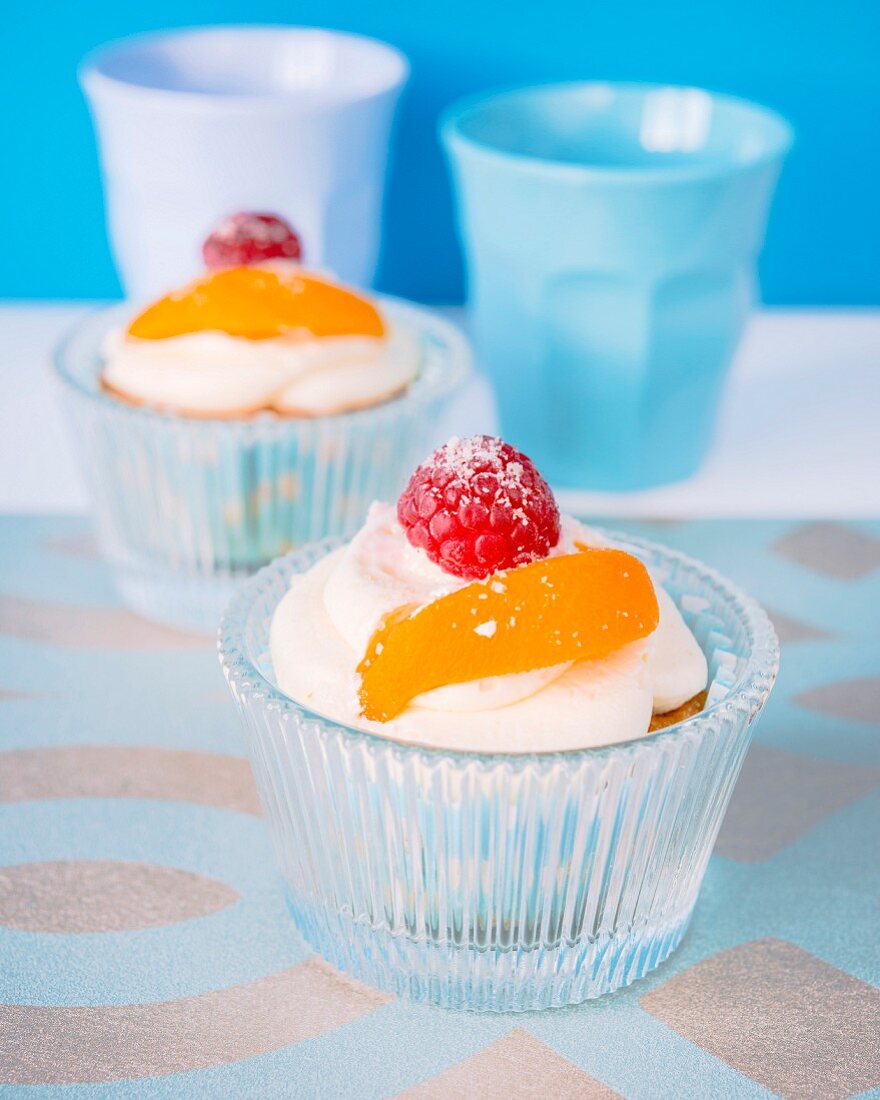 Cupcakes with cream frosting, a raspberry and apricot on the top