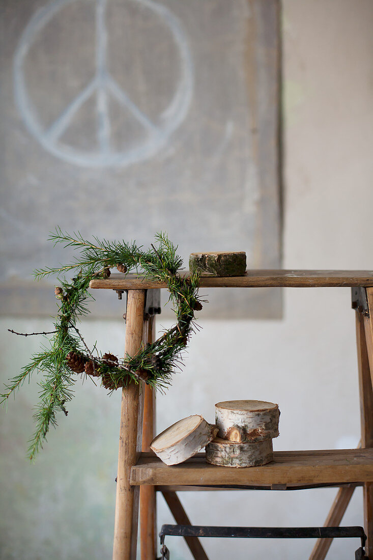 Wreath of larch twigs with cones on old wooden stepladder