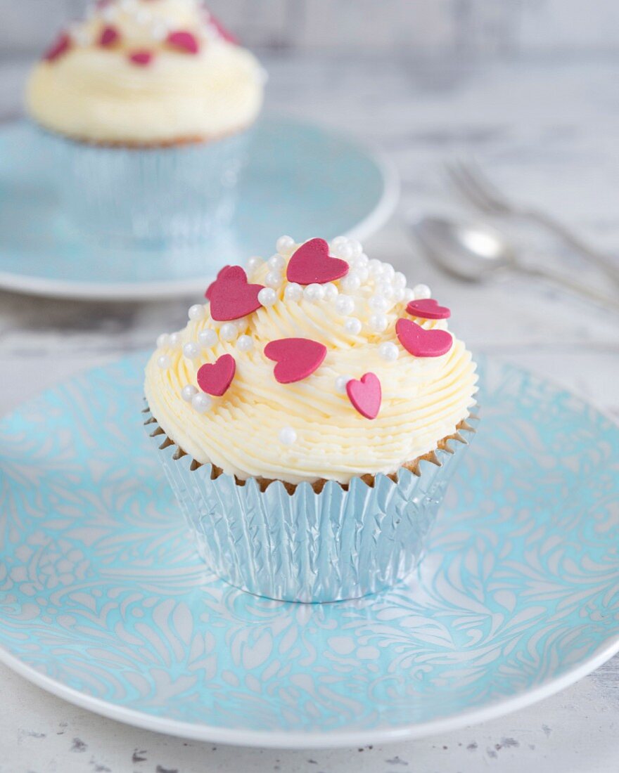 Cupcake mit Buttercreme und roten Zuckerherzen