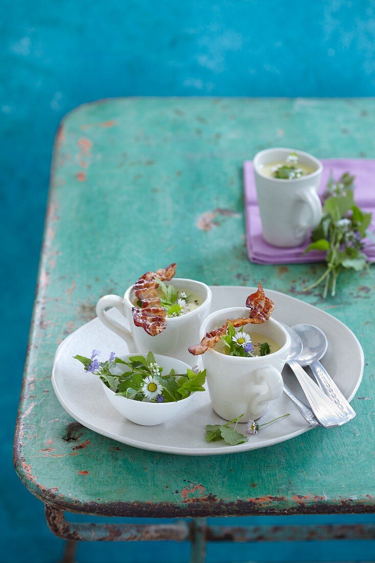 Wild herb soup with daisies and crispy bacon