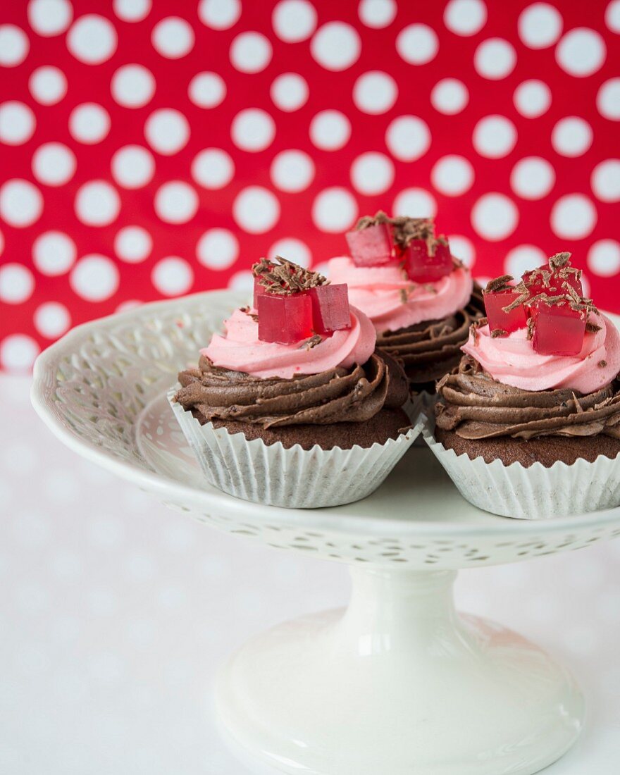 A cupcake with chocolate and raspberry cream and jelly cubes